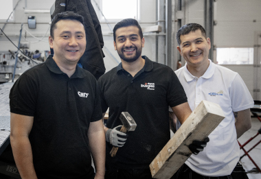 Tre personer som jobber hos Cary Bussglass, Dansk bussglas og Svensks bussglas står på verksted.