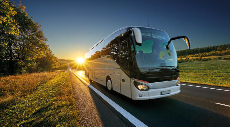 En buss kjører på en vei ved solnedgang