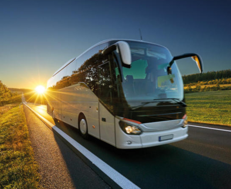 En buss kjører på en vei ved solnedgang